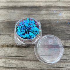 Close-up of multichrome eye shadow flakes shimmering with shifting iridescent hues in a textured finish