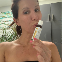 Cleanse Kind Daily Cleanser bottle, white and gold label, held by woman with pink nails