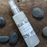 Clarifying toner spray bottle, frosted glass with silver cap, Ageless Botanicals label with floral design