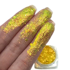 Yellow iridescent glitter flakes on fingers and in a small jar, for cosmetic use