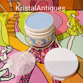 Eye makeup blue eyeshadow in white container with floral design and gold handle