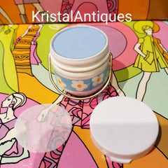 Eye makeup blue eyeshadow in white container with floral design and gold handle