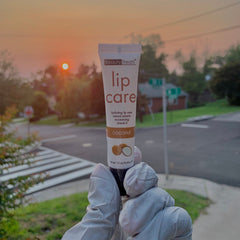 Lip care tube in white with brown text, held by gloved hands, Beauty Treats brand visible