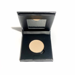Close-up of pressed mineral eyeshadow in warm golden hues with smooth, pigmented texture in eco-friendly paperboard compact