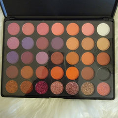 Close-up of 35 vibrant eyeshadow shades in matte, shimmer, and metallic finishes arranged in circular pans