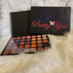 Close-up of fingertips applying shimmery taupe eyeshadow from palette to eyelid