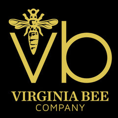 Close-up of hand applying Virginia Bee cream to cheek, showing rich texture blending into skin