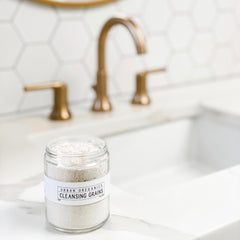 Cleansing grains in glass jar with white label, light beige powder, bathroom setting