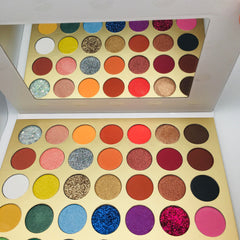 Eyeshadow palette with multiple colors, glitter, and matte finishes in a gold case