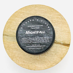 Activated charcoal face mask in black container on light wood surface, Nightfall by Chinesha's Closet