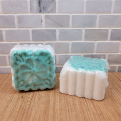 Bath bombs with green and white color, floral pattern, wrapped in plastic on wood surface