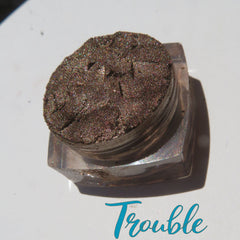Close-up of loose chocolate brown eyeshadow with gold shimmer particles, showcasing vegan mineral texture