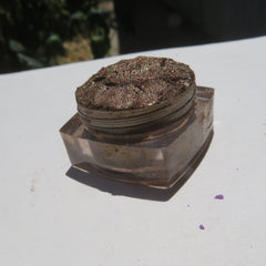 Side view of loose chocolate brown gold shimmer eyeshadow with reflective mineral particles in eco-friendly packaging