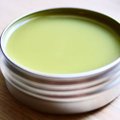 Green balm in silver tin, smooth pale green color, metallic container, on wood surface