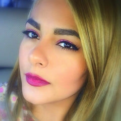 Close-up of fingers applying shimmery silver vegan eyeshadow to eyelid with soft blending brush