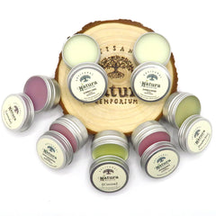 Lip balms in silver tins with Natura Emporium branding, various colors on wooden base