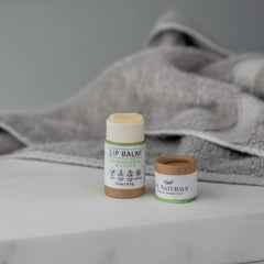 Lip balm in white and brown tubes with green label, jnlnaturals brand visible, on a white surface