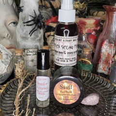 Bottles and jars with black, white, and clear containers, labels, and corks, with dried branches and a spider decoration