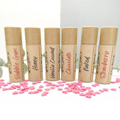 Lip balms in brown cardboard tubes with flavor labels, Pure Bubs brand, and pink heart confetti