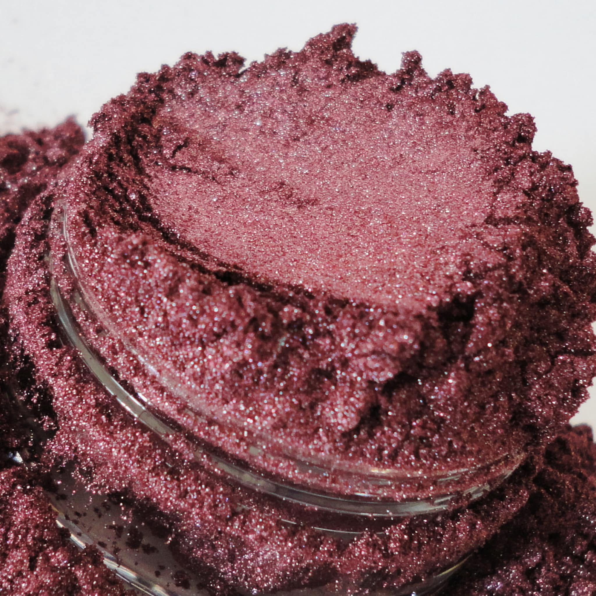 Mineral eye shadow in burgundy color with glitter texture in a jar.