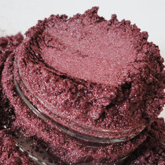 Mineral eye shadow in burgundy color with glitter texture in a jar.