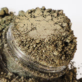 Eyeshadow in metallic brown with shimmer, visible in a clear container, close-up shot