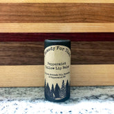 Lip balm tube with black cap, paper label, and text "Remedy For That