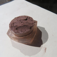 Eyeshadow, dark brown powder, clear glass jar, cosmetic product