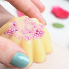 Yellow floral wax melt with pink sprinkles, held by hand