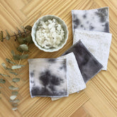 Reusable makeup remover pads, black tie-dye fabric, white terry cloth, on wooden surface