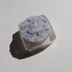 Close-up of matte gray loose pigment eyeshadow with fine powder texture in eco-friendly packaging
