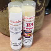 Lip balm tubes with white labels, Grubby Goat Soap branding, and clear caps