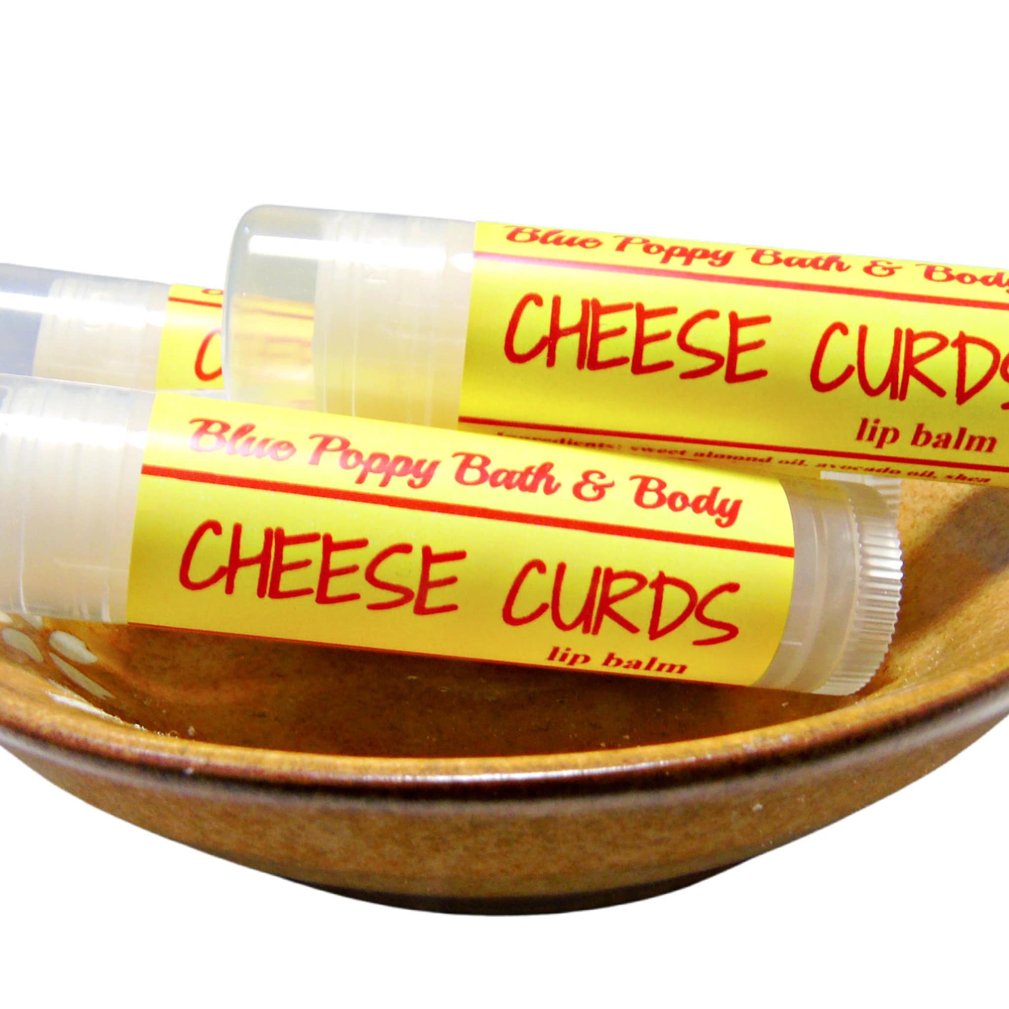 Lip balm tubes with yellow labels, red text, and clear plastic, in a brown bowl Blue Poppy Bath & Body