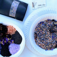 Billie Bee Products logo on a card next to white plates with colorful salts and flowers