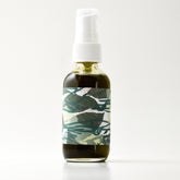 Facial cleanser bottle with white pump, green liquid, and patterned label