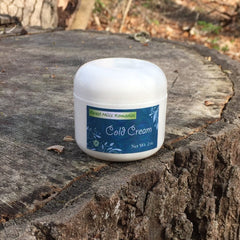 Cold cream jar, white plastic container, blue label with "Cold Cream" text, on wood surface