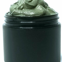 Close-up of black charcoal and golden turmeric face mask in a jar with creamy texture