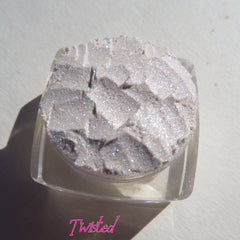 Glittery eyeshadow in a clear jar, silver and white with TWISTED logo visible