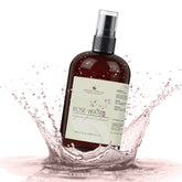 Rose water spray bottle, brown glass bottle, black cap, with water splash around it