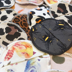 Reusable face wipes with assorted patterns, white stitched edges, and various fabric designs