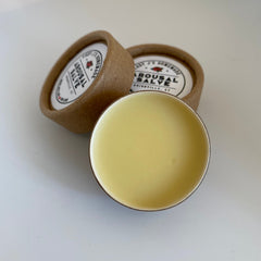 Arousal salve in brown cardboard container with yellow balm, Lady J's Homemade label visible