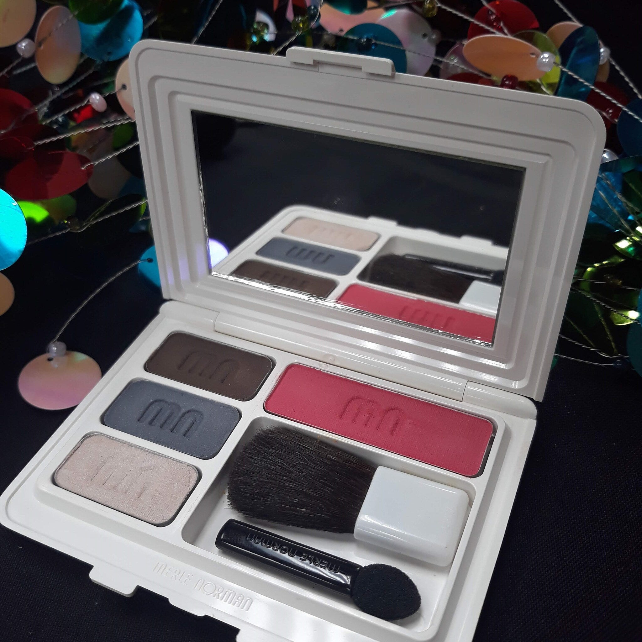 Face powder compact with white case, eyeshadow, blush, and Merle Norman branding