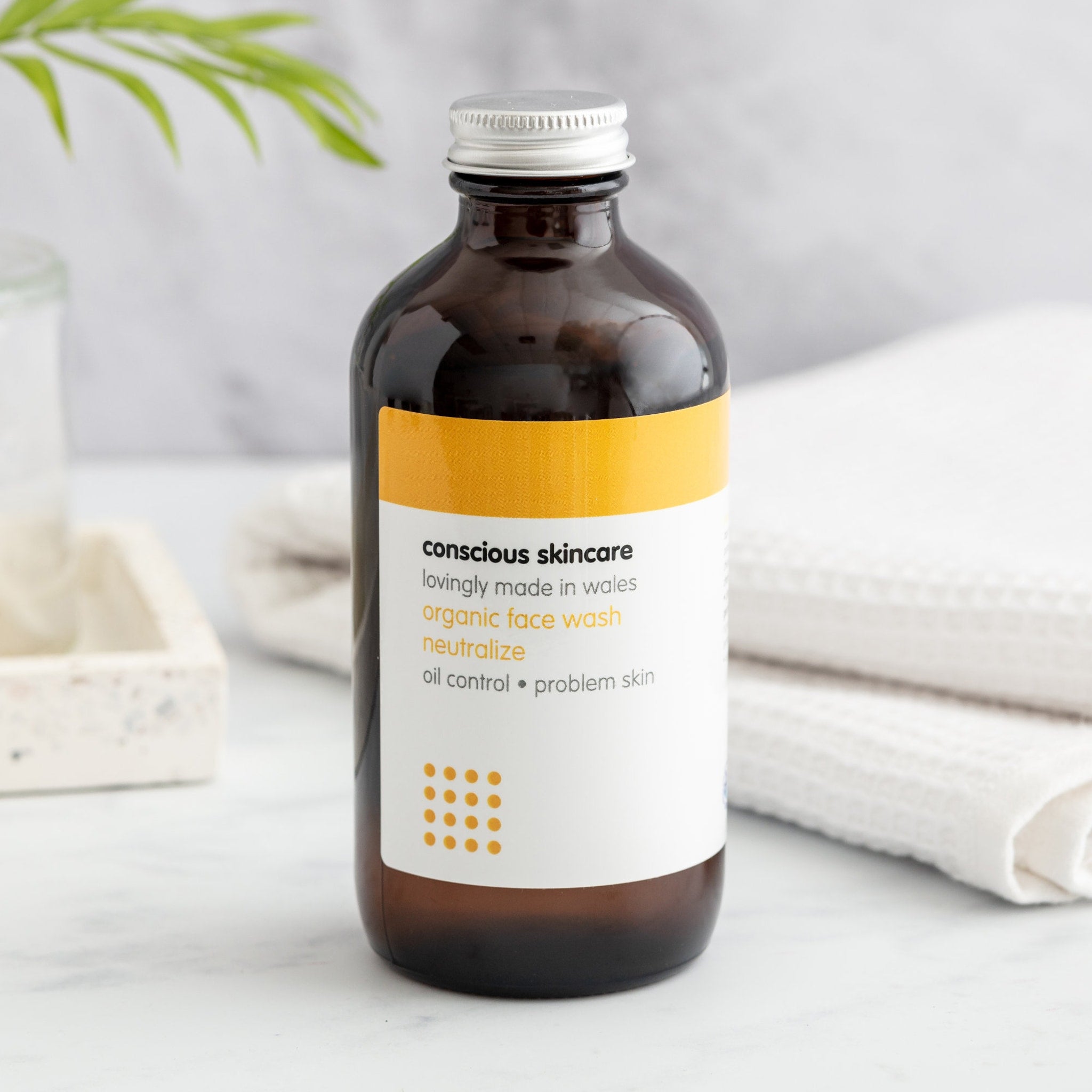 Organic face wash, brown glass bottle with silver cap, Conscious Skincare label visible
