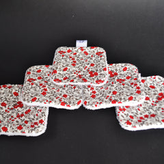 Floral patterned fabric squares with red flowers and white trim, arranged on black surface