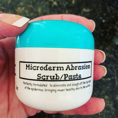 Microderm Abrasion Scrub/Paste, white and turquoise jar held in hand, label visible
