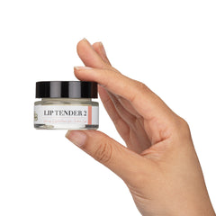 Lip balm jar with black lid, white label, and clear glass held in hand