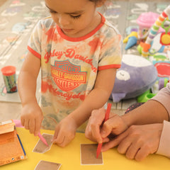 Harley Davidson tie-dye t-shirt with red trim, child coloring with pink crayon on yellow table