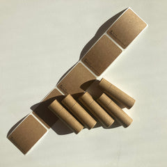 Kraft paper tubes with matching labels, brown and cylindrical, arranged on white surface