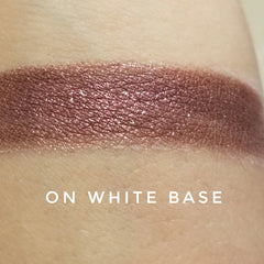 Close-up of warm cinnamon brown eye shadow with shimmering gold flecks in compact case