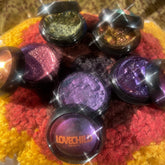 Pressed eyeshadow pots with duochrome shimmer and LOVECHILD branding on colorful background